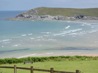 a bench sitting on the beach near the ocean at Manor Cottage in Crantock