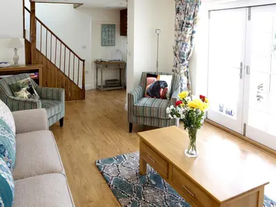 a living room with a vase of flowers on a coffee table at Manor Cottage in Crantock