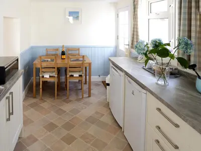 a kitchen with a table with a bottle of wine at Manor Cottage in Crantock