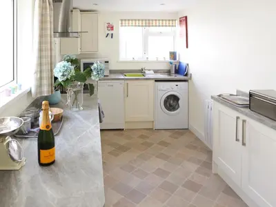 a kitchen with a sink and a washing machine at Manor Cottage in Crantock