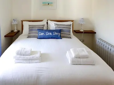 a large white bed with a blue sign on it at Manor Cottage in Crantock