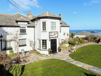 a white house with the ocean in the background at Manor House in Crantock