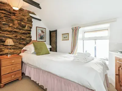 a bedroom with a bed and a stone wall at Manor House in Crantock