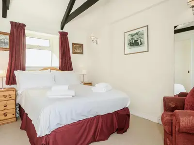 a bedroom with a large white bed with red curtains at Manor House in Crantock