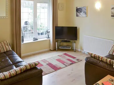 a living room with a couch and a flat screen tv at The Old Butchers in Crantock
