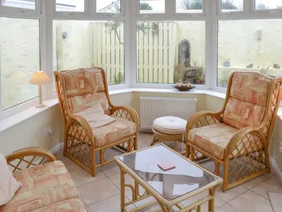 a living room with chairs and a table and windows at The Old Butchers in Crantock