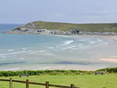 two benches sitting on the grass near a beach at The Old Butchers in Crantock