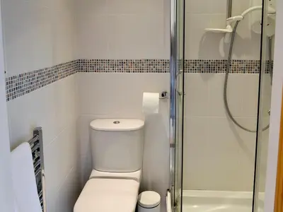 a bathroom with a toilet and a glass shower at The Old Butchers in Crantock