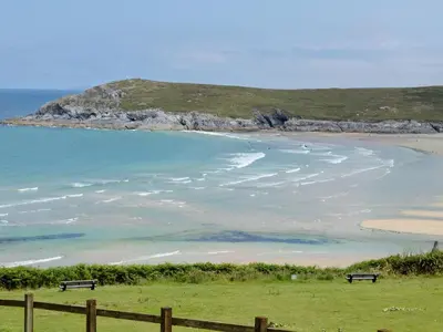 two benches sitting on the grass near a beach at North Shore in Crantock