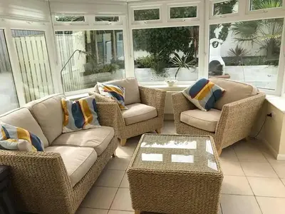 a screened in porch with wicker furniture and windows at North Shore in Crantock