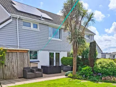 a house with a palm tree in the yard at Sweet Briar in Newquay