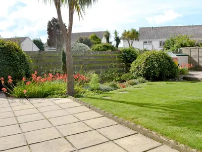 a garden with a palm tree and a fence at Sweet Briar in Newquay
