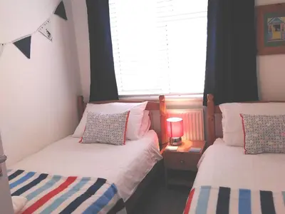 two twin beds in a room with a window at Sweet Briar in Newquay
