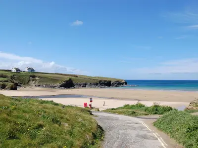 a dirt road leading to a beach with the ocean at Treyarnon in St Merryn
