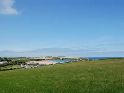 a green field with a beach and the ocean at Fistral in St Merryn