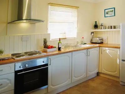 a kitchen with white cabinets and a stove top oven at Fistral in St Merryn