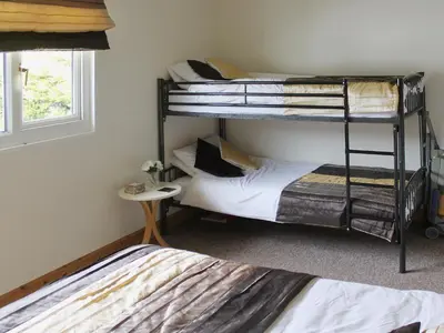 a bedroom with two bunk beds and a window at Fistral in St Merryn