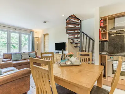 a kitchen and living room with a wooden table at Creekside in Little Petherick