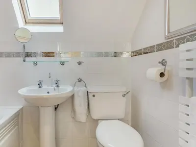 a white bathroom with a toilet and a sink at Creekside in Little Petherick