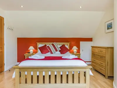 a bedroom with a large bed with red walls at Creekside in Little Petherick
