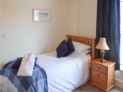a bedroom with a bed and a lamp on a night stand at Sandpipers in Padstow