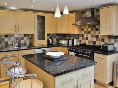 a kitchen with wooden cabinets and a black counter top at Sandpipers in Padstow