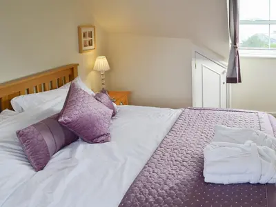 a bed with purple and white pillows on it at Sandpipers in Padstow