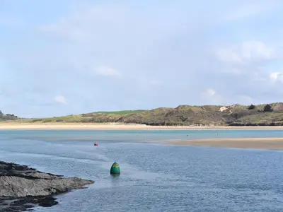 a green buoy in the water next to a beach at The Yellow House in Padstow