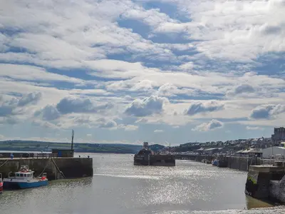 a river with boats in the water under a cloudy sky at The Yellow House in Padstow