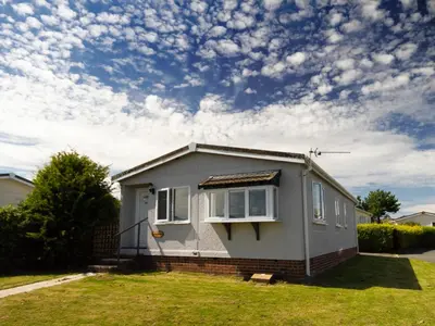 a small house in a yard with a cloudy sky at Lazy Daize in St Merryn