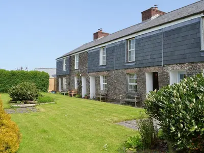 an old brick building with a lawn in front of it at 7 Quarrymans Cottage in Wadebridge