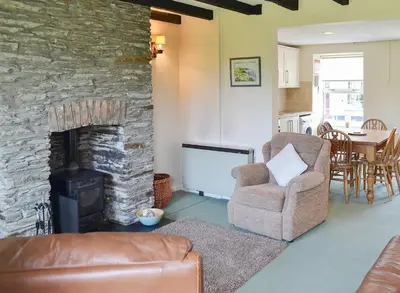 a living room with a stone fireplace and a chair at 7 Quarrymans Cottage in Wadebridge