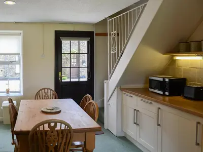 a kitchen with a wooden table and a microwave at 7 Quarrymans Cottage in Wadebridge