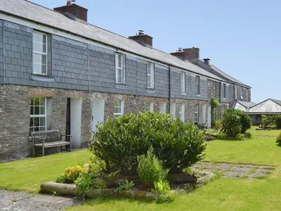 a row of brick houses with a bench in a yard at 7 Quarrymans Cottage in Wadebridge