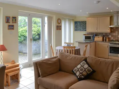 a living room with a couch and a kitchen at Sea Shells in Padstow