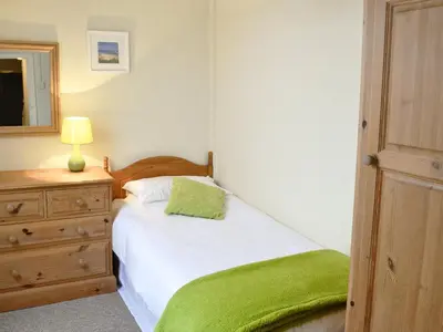 a bedroom with a bed with a green blanket on it at Nan-Tis in St. Issey