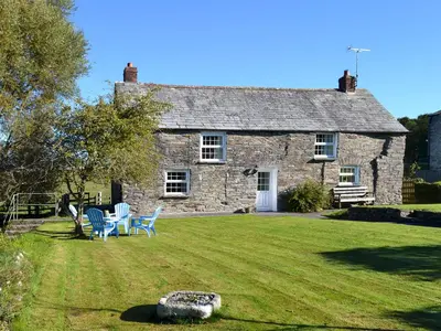 an old stone house with blue chairs in the yard at Nan-Tis in St. Issey