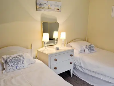 a bedroom with two beds with a mirror and a dresser at Nan-Tis in St. Issey