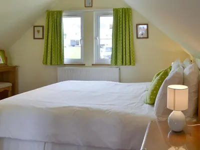 a bedroom with a white bed and two windows at Spring Tides in Padstow