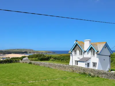a white house on a hill with the ocean in the background at St Cadoc Cottage in St Merryn
