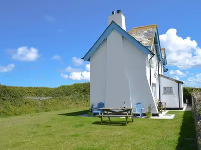 a white house with a picnic table in the yard at St Cadoc Cottage in St Merryn
