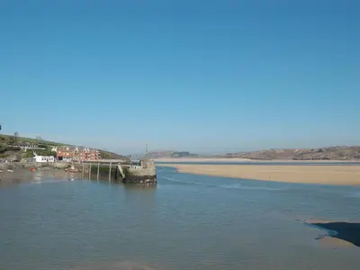 a pier in the water next to a beach at St Cadoc Cottage in St Merryn