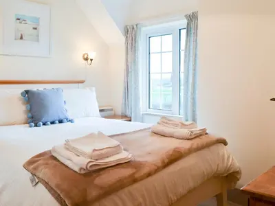 a bedroom with a bed with towels on it at St Cadoc Cottage in St Merryn