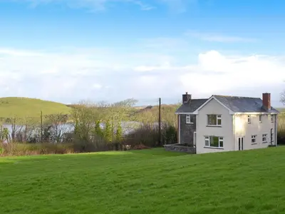 a white house in a field with a green field at Tregunna Cottage in Wadebridge