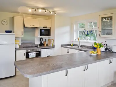 a kitchen with white cabinets and a granite counter top at Tregunna Cottage in Wadebridge