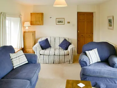 a living room with two blue chairs and a couch at Tregunna Cottage in Wadebridge