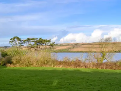 a lake in a field next to a grass field at Tregunna Cottage in Wadebridge