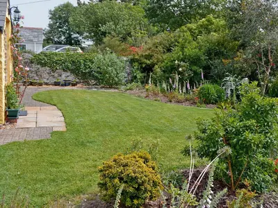 a garden with green grass and plants at Dover Row Cottage in Zelah