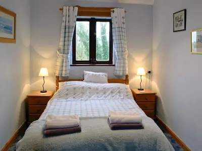 a bedroom with a bed with two lamps and a window at Roosters Perch in Saint Kew