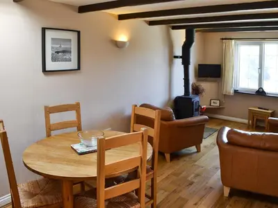 a living room with a table and a wood stove at Cobblers Cottage in Port Isaac